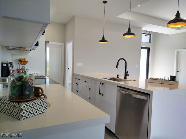 kitchen featuring a center island with sink, sink, hanging light fixtures, stainless steel dishwasher, and white cabinetry