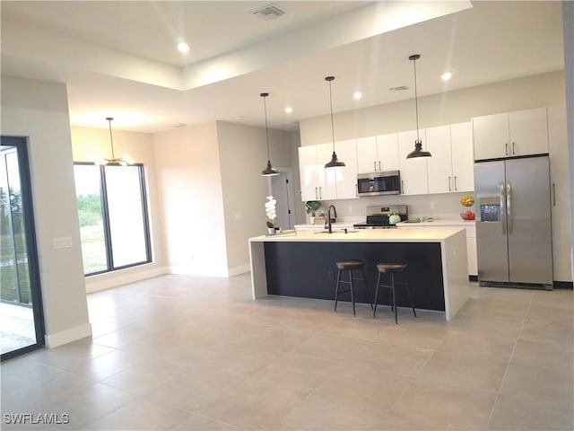 kitchen with white cabinetry, sink, hanging light fixtures, a kitchen island with sink, and appliances with stainless steel finishes