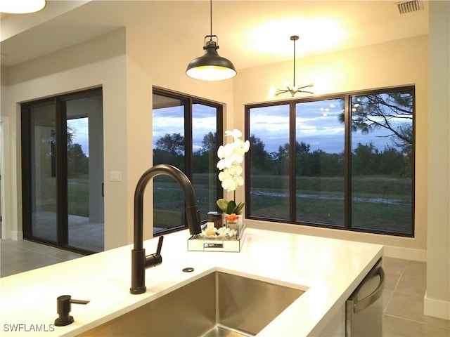 kitchen with dishwashing machine, sink, pendant lighting, light tile patterned floors, and a chandelier