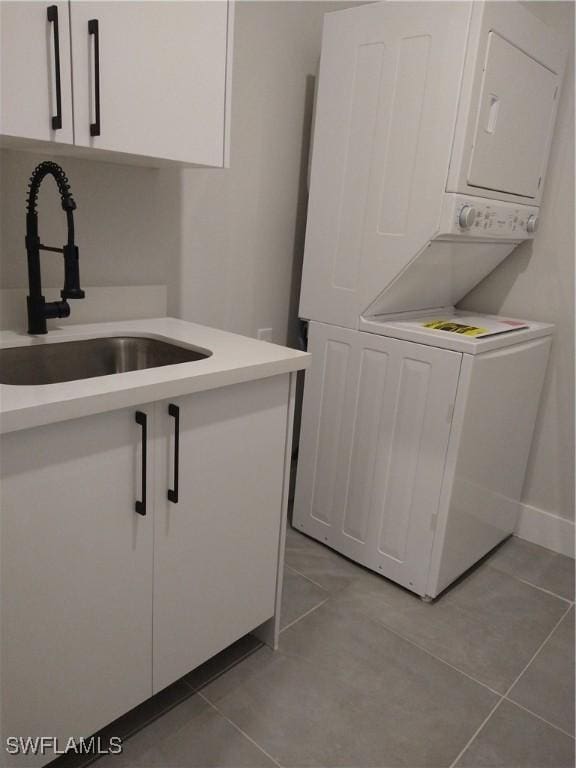 washroom with sink, light tile patterned floors, cabinets, and stacked washer / drying machine