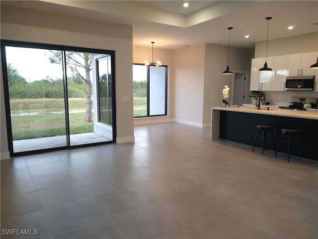 kitchen featuring hanging light fixtures, tile patterned flooring, a notable chandelier, white cabinetry, and stainless steel appliances