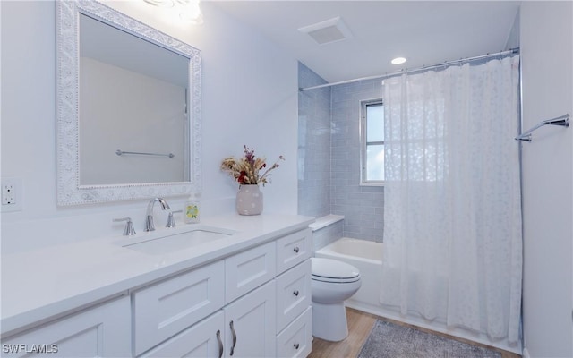 full bathroom featuring wood-type flooring, vanity, shower / tub combo, and toilet