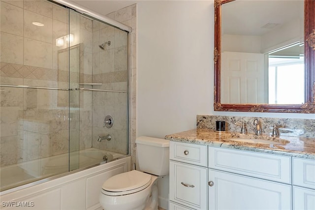 full bathroom with vanity, enclosed tub / shower combo, and toilet