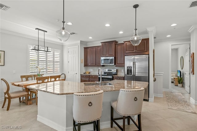 kitchen featuring an island with sink, appliances with stainless steel finishes, light stone countertops, and sink