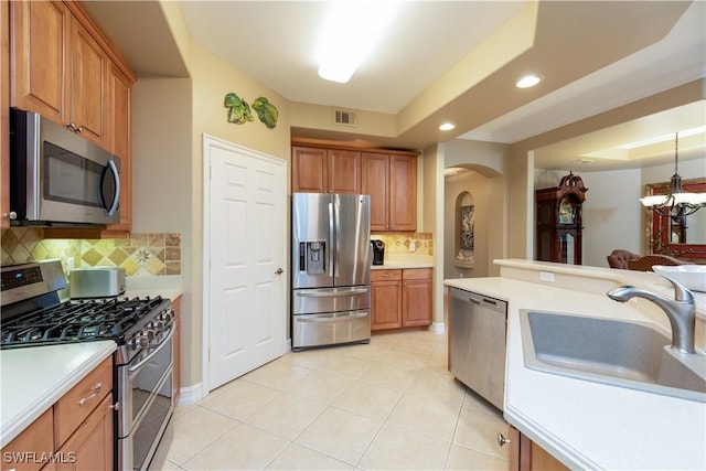 kitchen with a tray ceiling, decorative backsplash, a notable chandelier, and appliances with stainless steel finishes