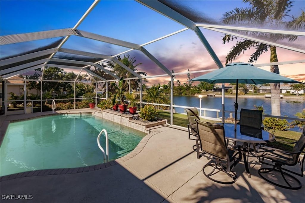 pool at dusk featuring a lanai, a water view, and a patio