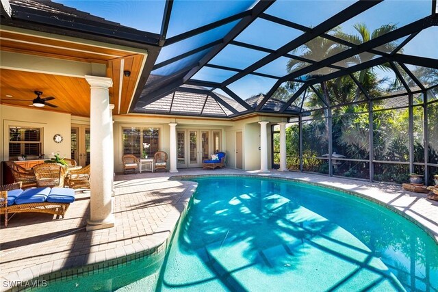 view of swimming pool with ceiling fan, outdoor lounge area, a patio area, and glass enclosure