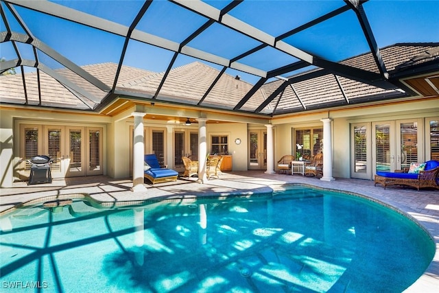 view of swimming pool with ceiling fan, a patio area, glass enclosure, and french doors