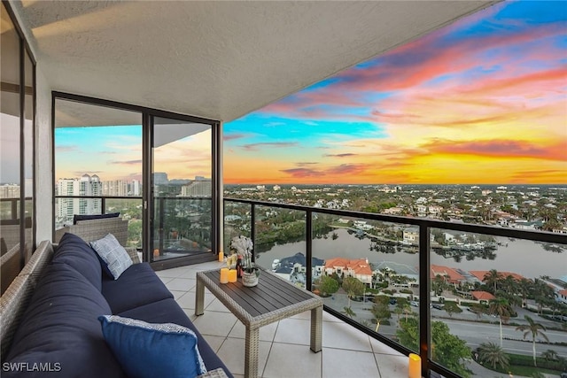 balcony at dusk featuring a water view and an outdoor hangout area