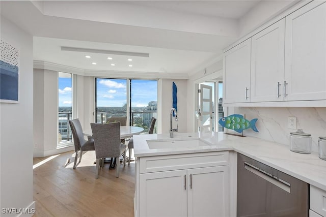 kitchen with tasteful backsplash, white cabinetry, sink, and light wood-type flooring