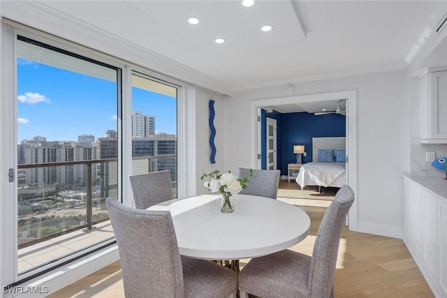 dining space with crown molding and light hardwood / wood-style floors