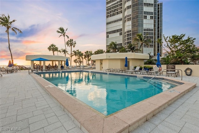 pool at dusk with a patio area