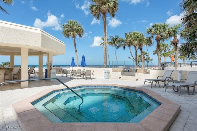 view of pool featuring area for grilling, a patio area, a community hot tub, and a water view