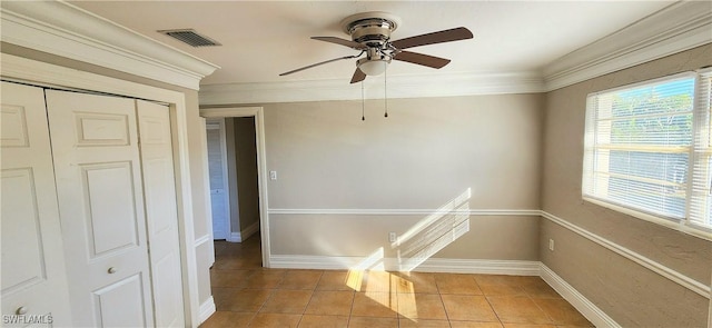 empty room with ceiling fan, ornamental molding, and light tile patterned floors