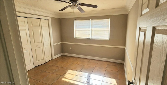 unfurnished bedroom with ceiling fan, a closet, light tile patterned flooring, and ornamental molding