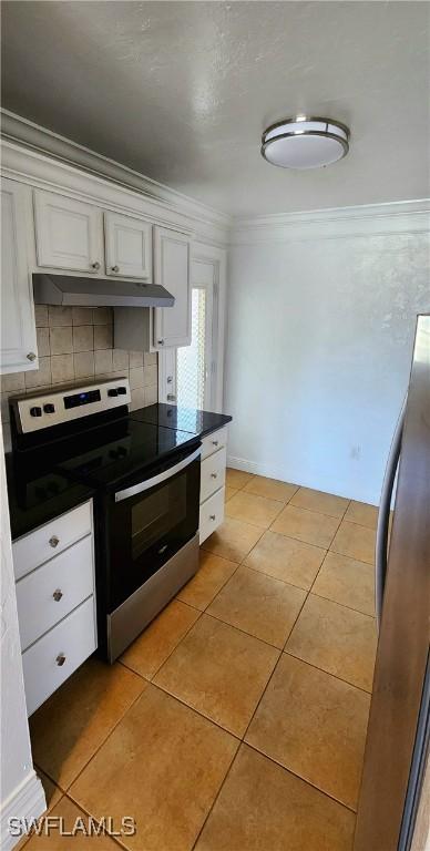 kitchen featuring light tile patterned floors, stainless steel appliances, tasteful backsplash, ornamental molding, and white cabinets