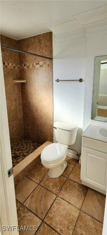 bathroom featuring a tile shower, vanity, and toilet