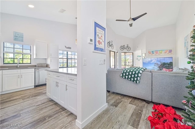 kitchen featuring light wood-type flooring, white cabinetry, stainless steel dishwasher, and sink