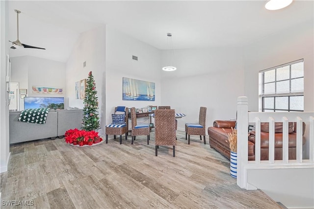 dining space with ceiling fan, high vaulted ceiling, and hardwood / wood-style flooring