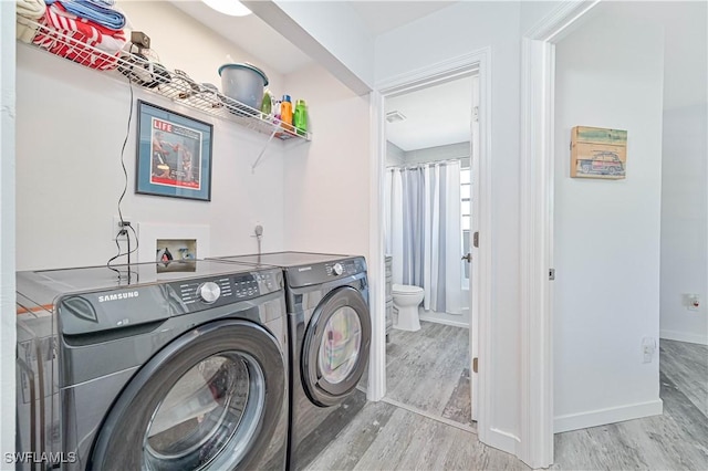 laundry area with washer and dryer and light hardwood / wood-style floors