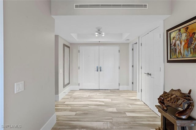 interior space with a raised ceiling and light hardwood / wood-style flooring