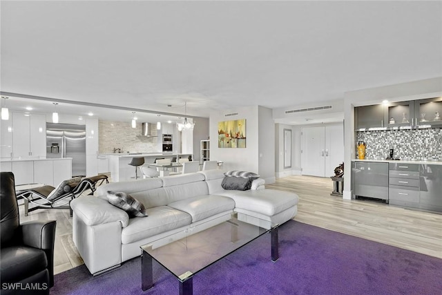 living room with light hardwood / wood-style floors, indoor bar, and a notable chandelier