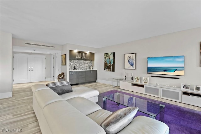 living room with bar and light hardwood / wood-style floors