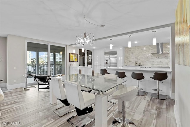 dining area with light hardwood / wood-style floors and an inviting chandelier