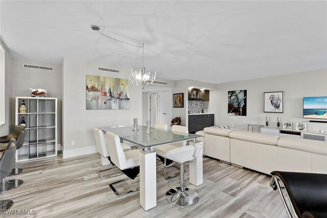 dining area with light hardwood / wood-style floors and a chandelier