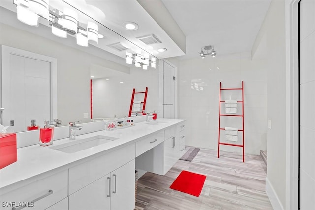 bathroom with tiled shower, vanity, and hardwood / wood-style flooring