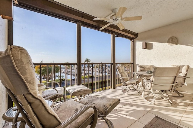 sunroom / solarium featuring ceiling fan, plenty of natural light, and a water view