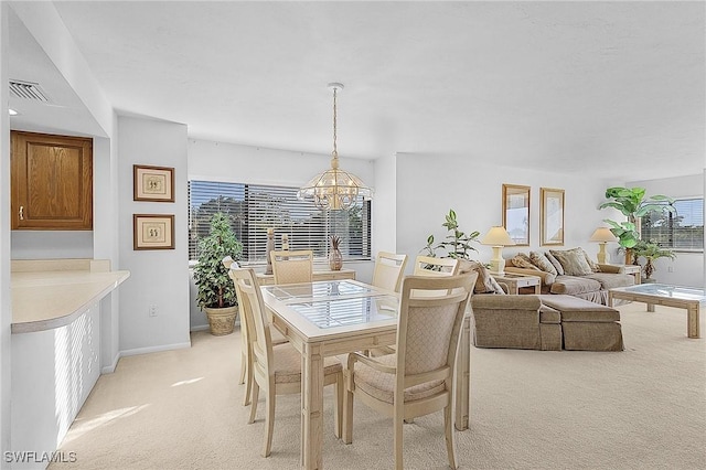 dining space with light carpet and a chandelier