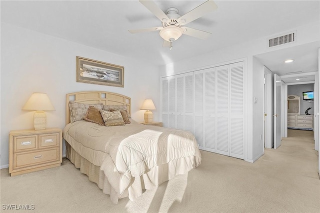 bedroom with ceiling fan, light colored carpet, and a closet