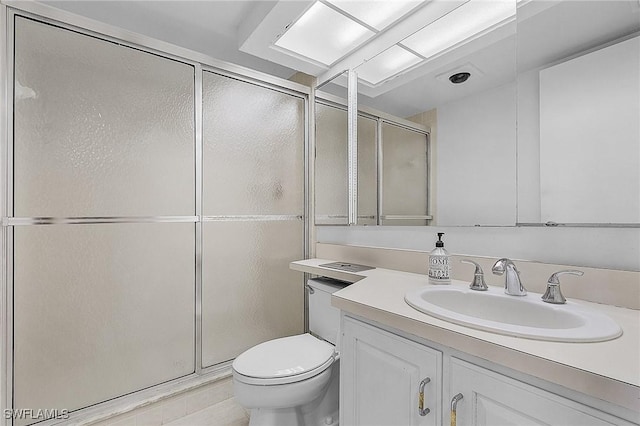 bathroom featuring tile patterned flooring, vanity, a shower with shower door, and toilet