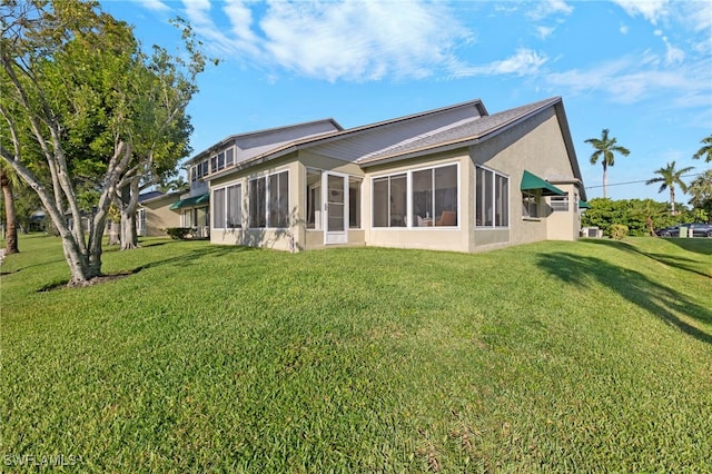 rear view of house featuring a lawn and a sunroom