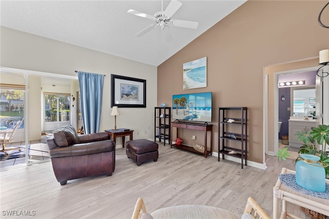 living room featuring ceiling fan, light hardwood / wood-style floors, a textured ceiling, and high vaulted ceiling