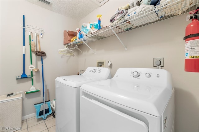 laundry room with washer and dryer, light tile patterned floors, and a textured ceiling