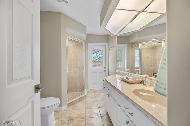 bathroom featuring toilet, vanity, tile patterned floors, and a shower with door