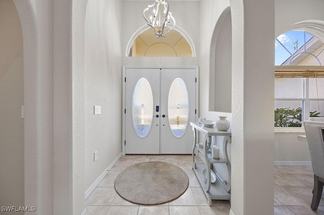 tiled entryway featuring a chandelier and french doors