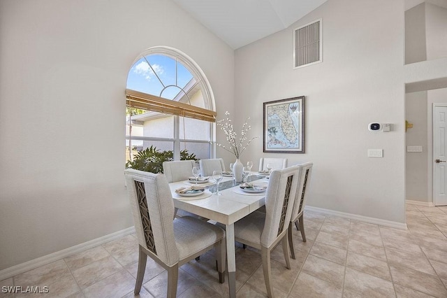 dining space featuring light tile patterned floors and high vaulted ceiling