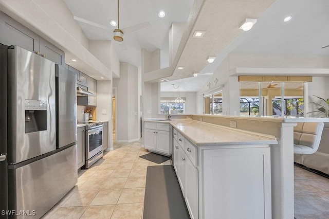 kitchen featuring kitchen peninsula, stainless steel appliances, ceiling fan, white cabinets, and hanging light fixtures