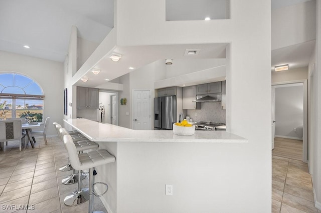 kitchen with tasteful backsplash, gray cabinetry, a breakfast bar, and stainless steel appliances