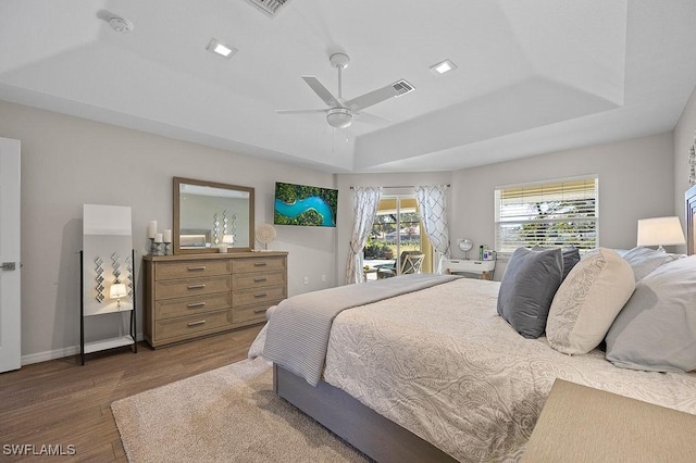 bedroom with a raised ceiling, ceiling fan, and dark hardwood / wood-style flooring