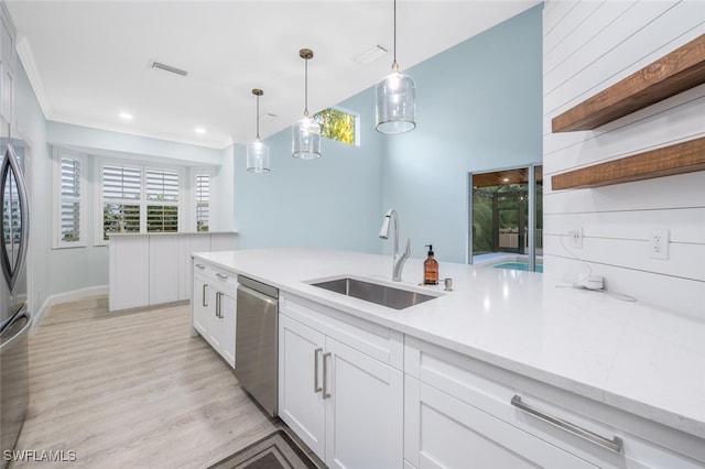 kitchen with sink, stainless steel dishwasher, pendant lighting, light hardwood / wood-style floors, and white cabinets