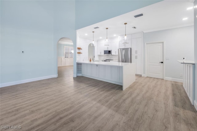 kitchen with pendant lighting, white cabinets, light hardwood / wood-style floors, kitchen peninsula, and stainless steel appliances