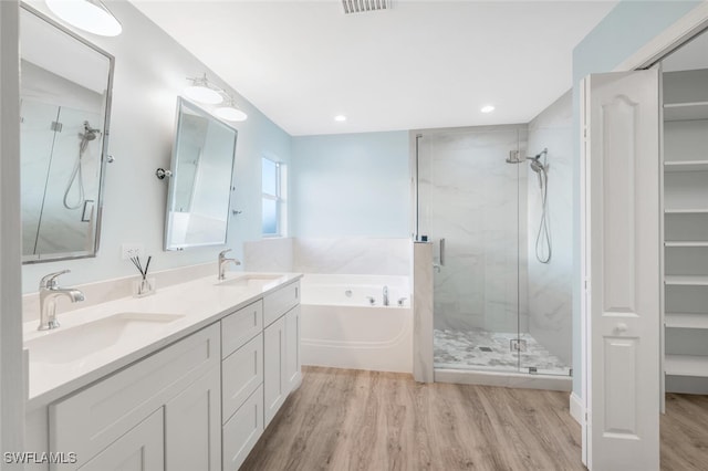 bathroom with plus walk in shower, hardwood / wood-style floors, and vanity