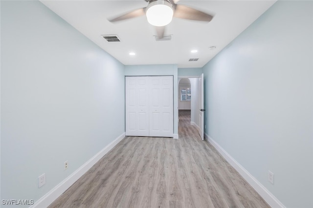 unfurnished bedroom with ceiling fan, light wood-type flooring, and a closet