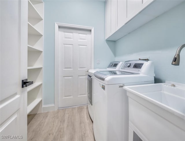 laundry area with cabinets, light hardwood / wood-style floors, and washing machine and clothes dryer