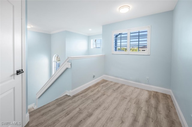 empty room featuring ornamental molding and light wood-type flooring