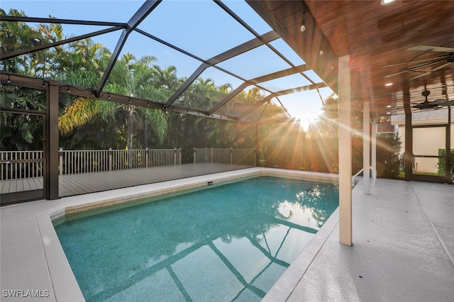 view of pool featuring glass enclosure, ceiling fan, and a patio